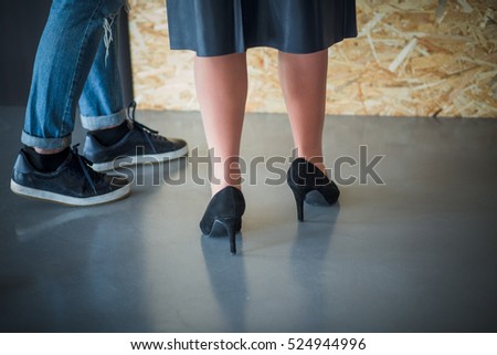 Low view of businesswoman's heels posing in office interior. Colleague lady talking with her colleague man in office. Business concept.