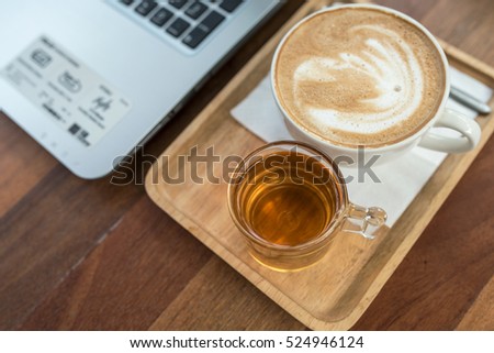 Cup of cappuccino and laptop on the table in cafe. Coffee break image background