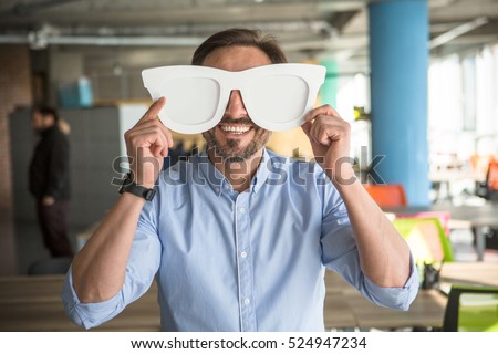 Happy businessman with funny glasses on showing to camera. Handsome happy man joking during work. Break time concept. Royalty-Free Stock Photo #524947234
