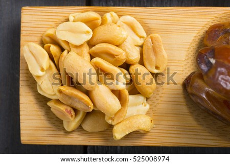 sun dried organic fruits, nuts and oil seeds on bamboo serving tray, black wooden table background