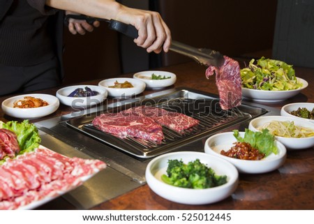 Korean BBQ Raw Beef on the Grill and Pickled Banchan Vegetables Royalty-Free Stock Photo #525012445