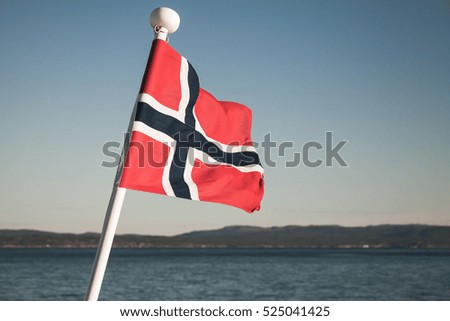 Norwegian national flag waving over blue sky background, vintage toned photo