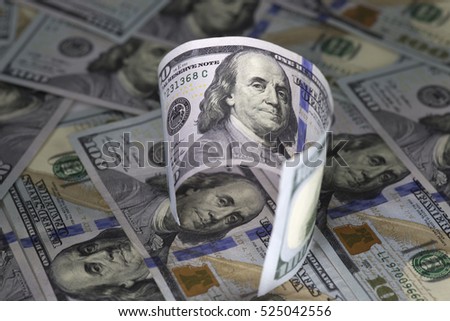 Curved hundred us dollar banknote standing on  hundred us dollar bills background. 
