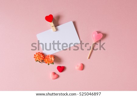 Valentine day composition: credit / visiting card template with clamp, spring flowers, candy and small hearts on light pink background. Top view.