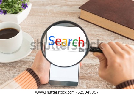 Search and modern lifestyle concept. Women hands Use the magnifying glass screen smart phone for search data on the desk.