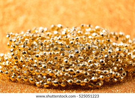 Golden bead and ribbon on gold glitter background