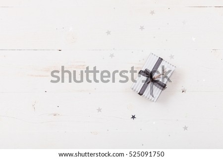 Top view on nice Christmas gift packed in striped paper  on wooden background. Presents and decor elements. Holidays and winter concept.