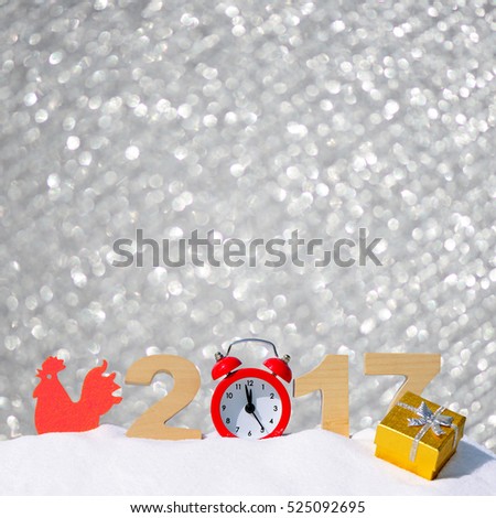 Happy new year 2017 greeting card. Alarm clock, red rooster and the numbers 2017 in a snowdrift on a silver glitter background