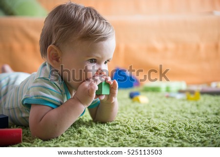 Sweet baby girl putting a toy in her mouth Royalty-Free Stock Photo #525113503