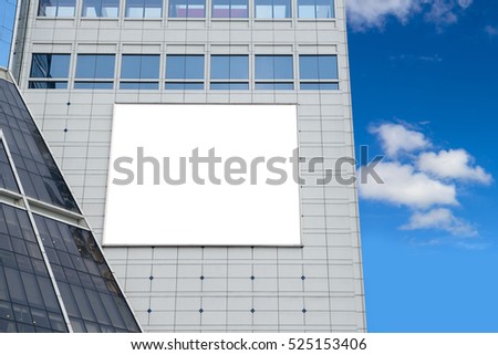 Blank advertising billboard in metallic frame with spotlight on modern office building or outside department store building in the city with blue sky background, useful for advertisement