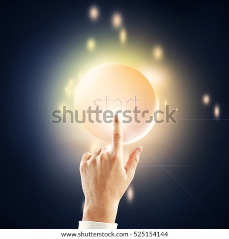 Hand pressing burning round start button on dark background