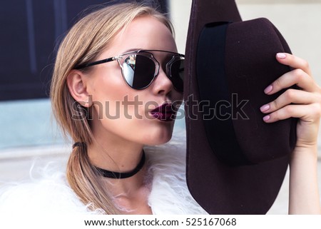 Happiness, consumerism, fashion and people concept - smiling young trendy hipster girl on city background in the sunlight outdoor.Sending kiss.