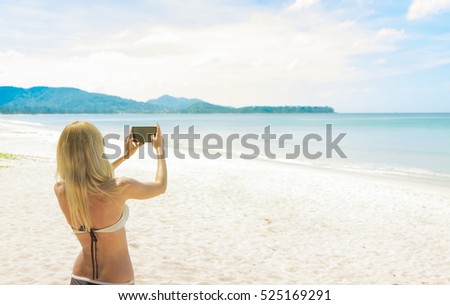 Woman tourist taking picture of beautiful beach in her smartphone. Vacation concept. 