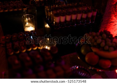Candles burn in glass among served fruits