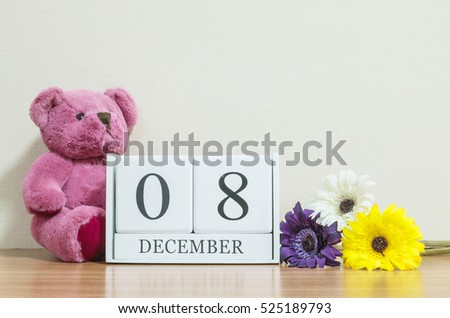 Closeup surface white wooden calendar with black 8 december word on brown wood desk and cream color wallpaper in room textured background with copy space , selective focus at the calendar
