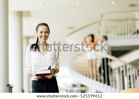 Beautiful woman holding books and smiling in a modern library