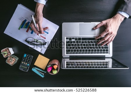 Top view of Businessman using laptop with analyzing investment charts on the office desk. Royalty-Free Stock Photo #525226588