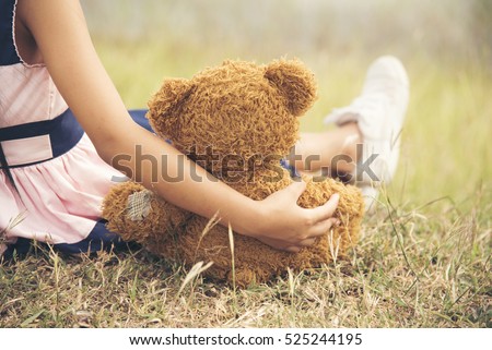 Teddy Bear picnic happy child girl kid holding fluffy toy with little hand sitting on grass field. cute girl love teddy bear best friends hug holding together. Kids on playground Picnic Best Friend Royalty-Free Stock Photo #525244195