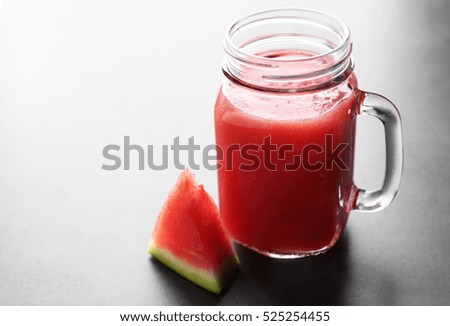Jug with smoothie and watermelon slice on grey table