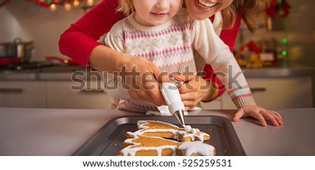 Happy mother and baby decorating homemade christmas cookies with glaze