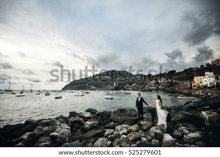 Bride and groom stand on the rocks before old Italian city