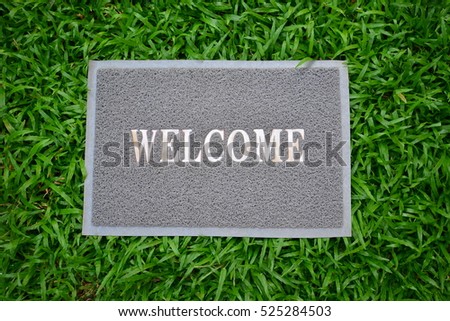gray welcome carpet on green grass