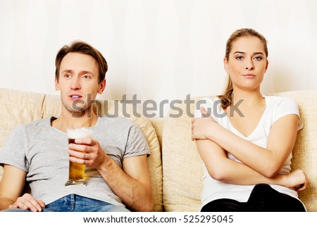Woman sitting bored while man watching sports