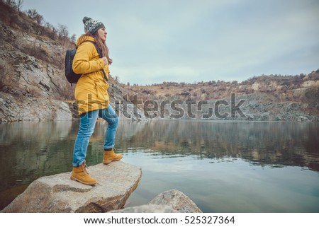 Woman in boots and jeans walks along the lake shore in autumn career