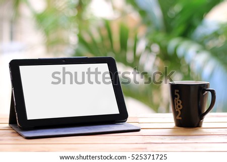 Tablet and a cup of coffee natural green backdrop.copy space.