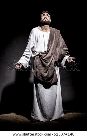 Jesus Christ praying to God consecration the bread and grapes in the dark black night. Black and white Royalty-Free Stock Photo #525374140