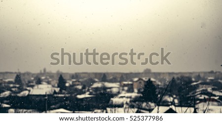 Snow falling down over the city.