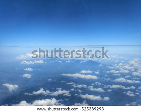 Clear blue sky and white clouds as seen from the airplane window.