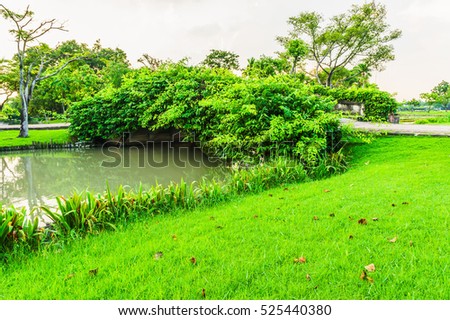 Landscape of forest bridge and canal are city park. This are blue sky time and grass on foreground on picture.