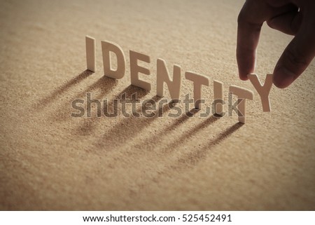 IDENTITY wood word on compressed board with human's finger at Y letter Royalty-Free Stock Photo #525452491