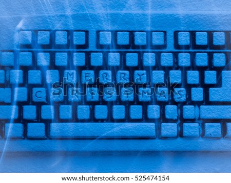 keyboard covered with snow with words Merry Christmas illuminated with blue light