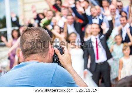 Wedding photographer in action, taking a picture of group of guests