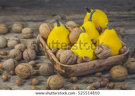 Decorative pumpkin and nuts in the wooden plate