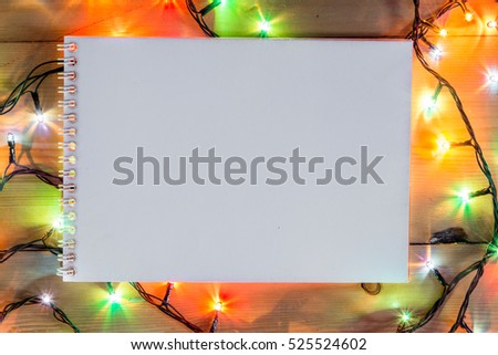 Christmas romantic lights frame on wooden background with open notebook. Decorative garland in wood copy  space. Clear perfect decoration for intimate evening dinner. Studio close up photo. Diary