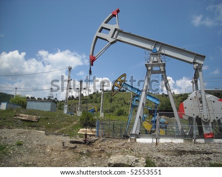 An oil pump jack in the middle of a mountain landscape
