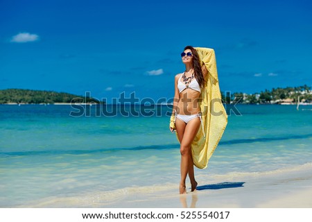 Summer portrait of a beautiful girl in bikini walking on a beach