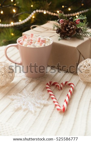 on the table is a large mug of hot cocoa with marshmallows, lie next to the delicious sweets and Christmas gift