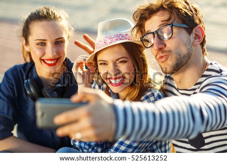 Friendship, leisure, summer, technology and people concept - smiling friends making selfie outdoors