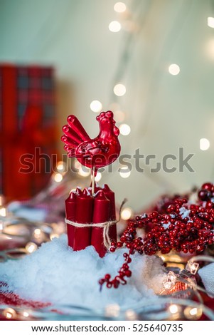 Christmas composition with red rooster lollipop with candles and red berries on the snow, on blurred bokeh light background. Red rooster  - symbol of New Year 2017.