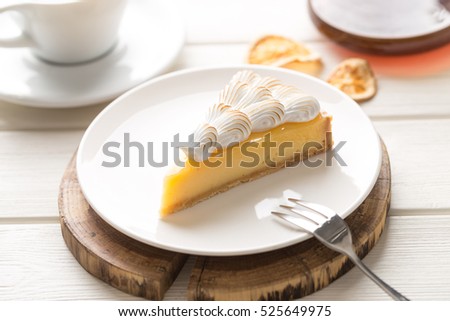 Lemon meringue pie with cup of coffee on white wooden background