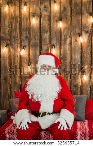 Traditional Santa Claus sitting on the couch and having a rest. Christmas. Red background.
