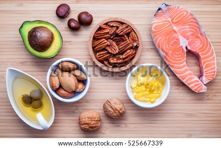 Selection food sources of omega 3 and unsaturated fats. Super food high vitamin e and dietary fiber for healthy food. Almond ,pecan ,hazelnuts,walnuts ,olive oil ,fish oil ,salmon  on cutting board. Royalty-Free Stock Photo #525667339