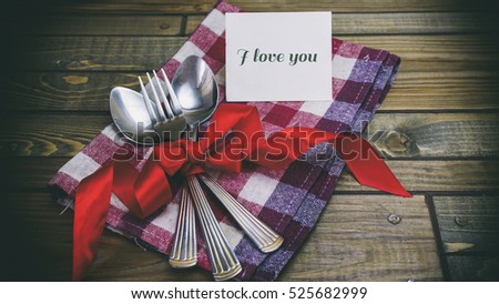 Festive spoons and forks on the wooden table, words on paper i love you