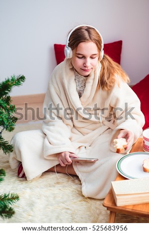 Young girl listening to Christmas carols through her headphones in the early morning