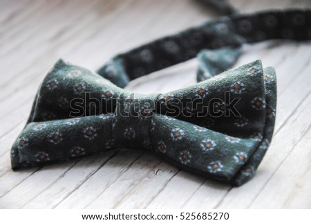 Green bow tie with a pattern on a wooden background. Accessory for formal dress.  Men's and women's accessories. Men's and women's bow tie. Men's casual.