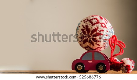 Wooden toy car with gift knitted bauble on a table isolated on gray background. empty copy space for inscription. 